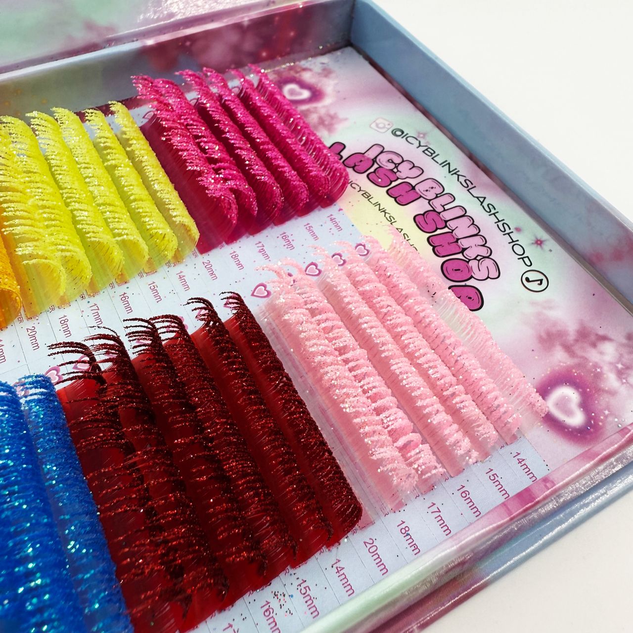 Set of false eyelashes in various colors displayed in a box.